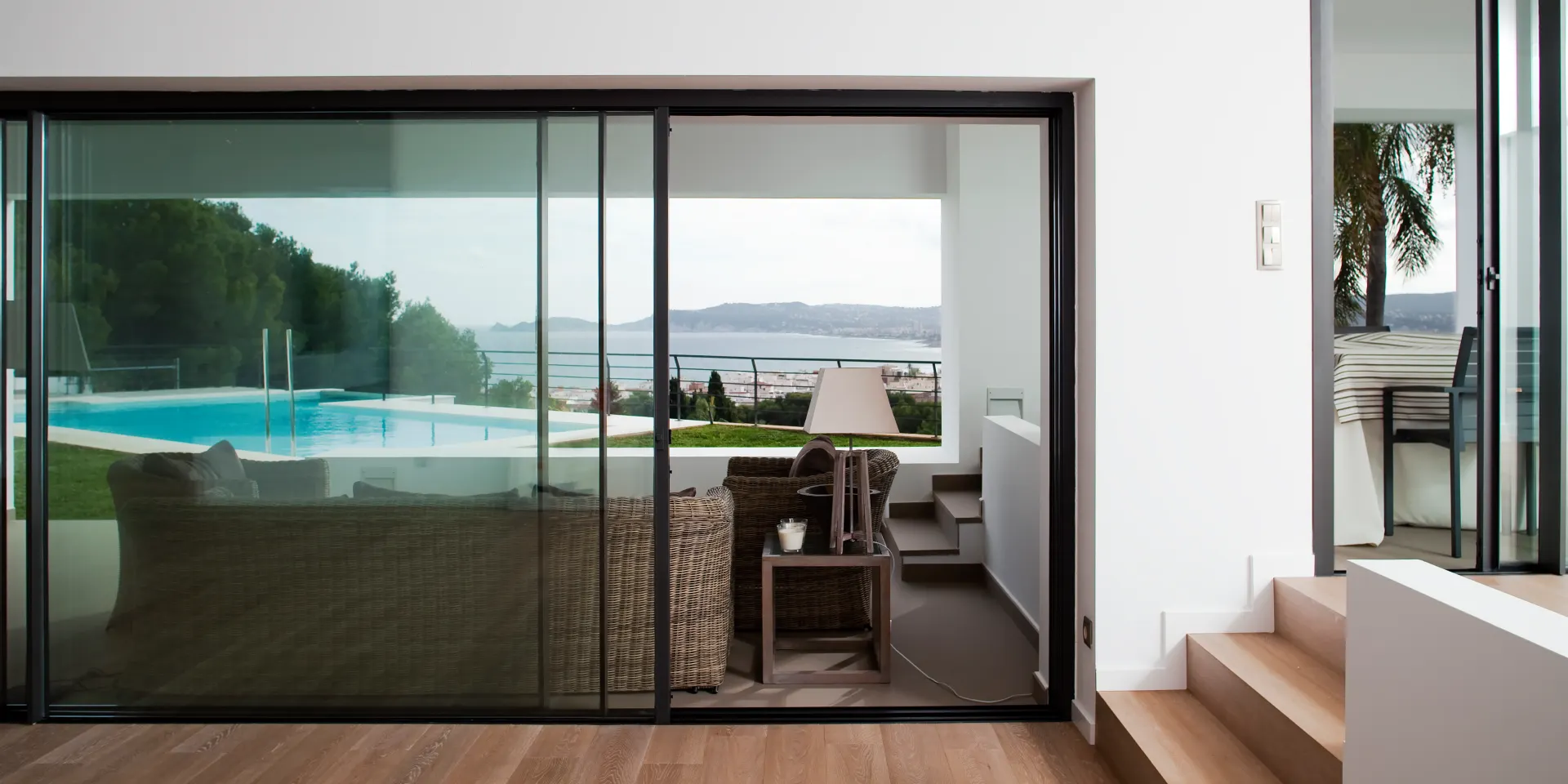 SunSeeker glass sliding patio doors in a contemporary home, with a double door configuration and one door partially open. The frames are made of aluminium and have a brown colour